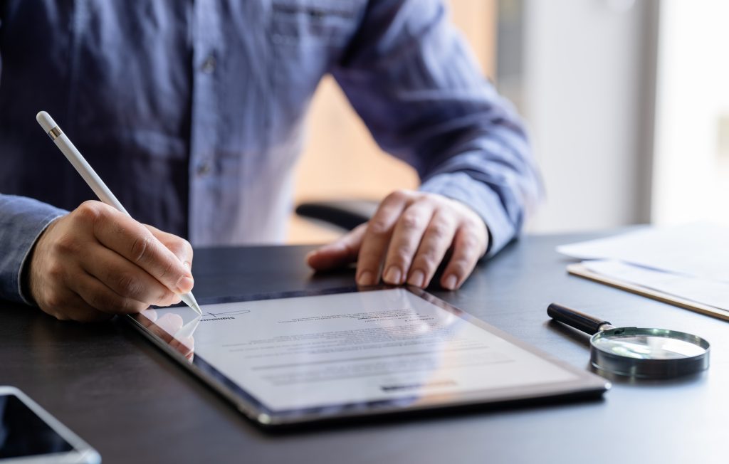 Man signing document on tablet