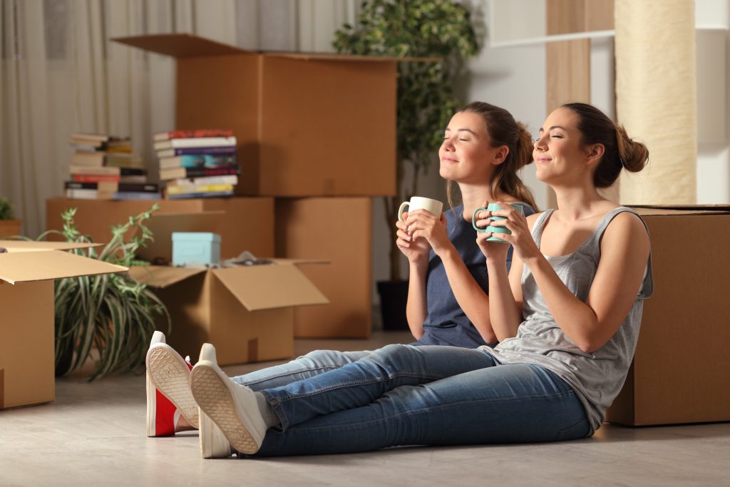 Happy roommates moving home resting breathing fresh air